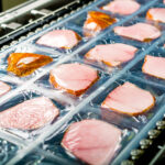 food processing production line with processed, packaged meats on it